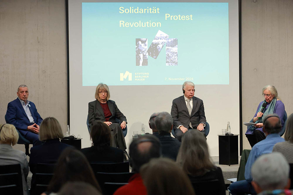 Personen sitzen auf einer Bühne 